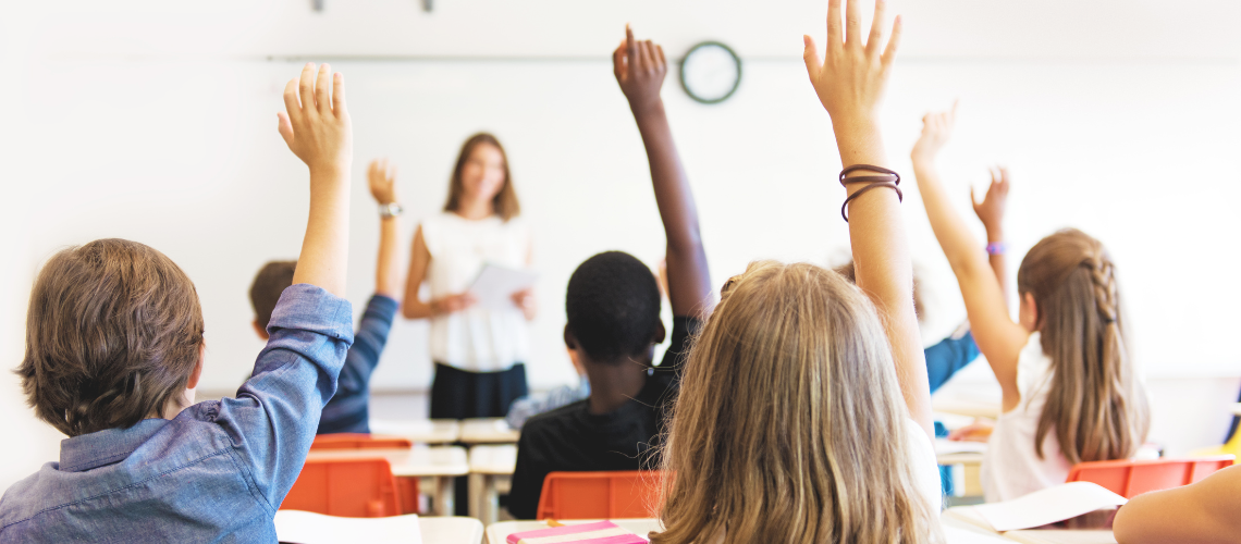 Students raising their hands in a classroom